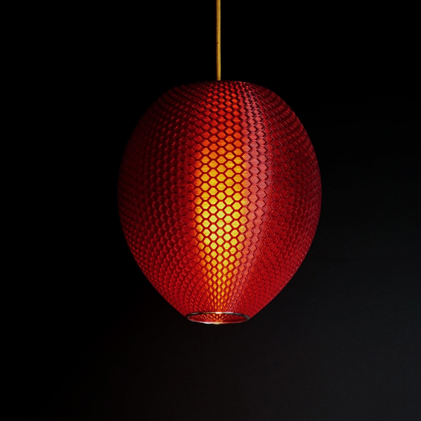 Crimson red sculptural pendant light illuminated, casting ambient glow and elegant reflections