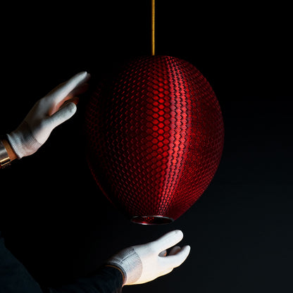 Side view of crimson red sculptural pendant light showing surface detail