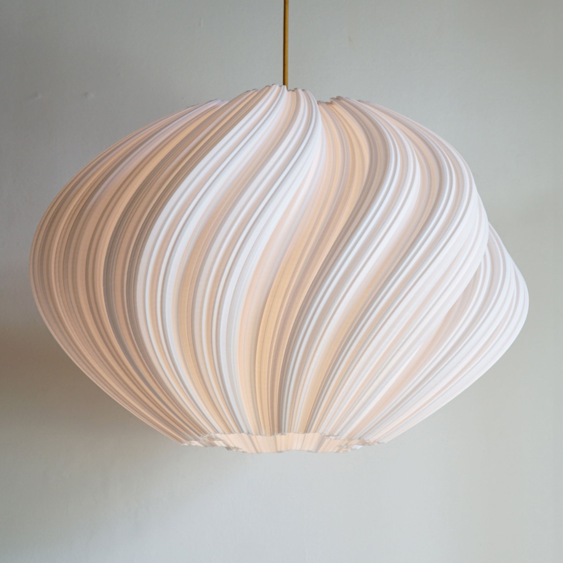 Large White Seashell Pendant Light illuminated, casting ambient glow and highlighting flowing spiral sculptural curves