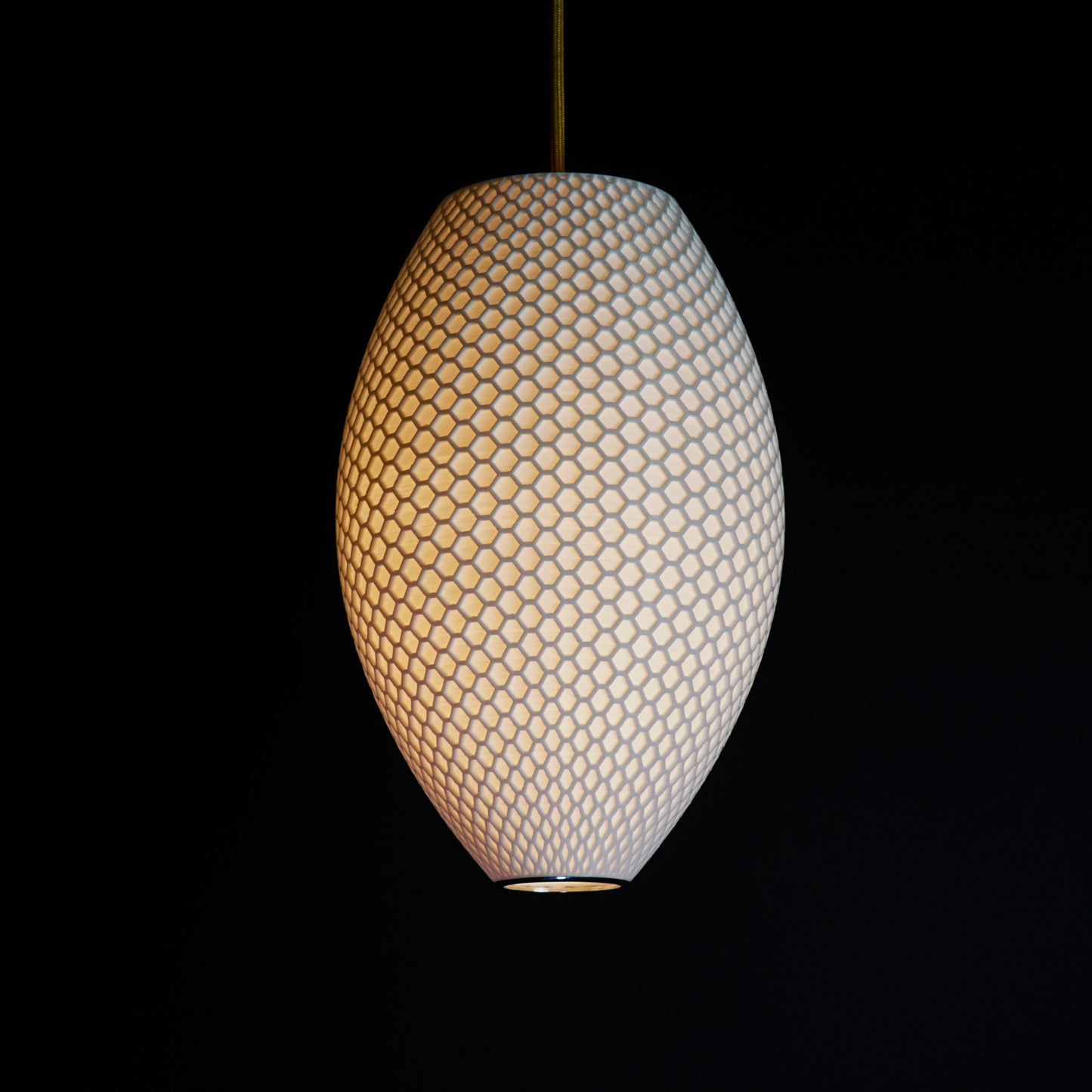 Long White Hive Pendant Light illuminated, casting soft ambient glow and highlighting geometric hive pattern