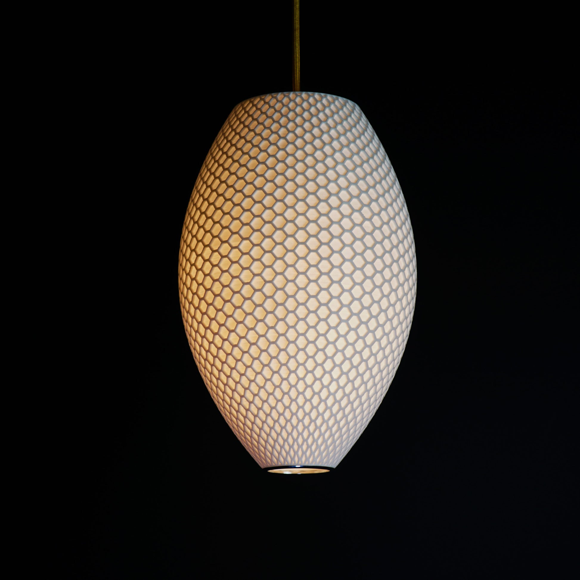 Long White Hive Pendant Light illuminated, casting soft ambient glow and highlighting geometric hive pattern