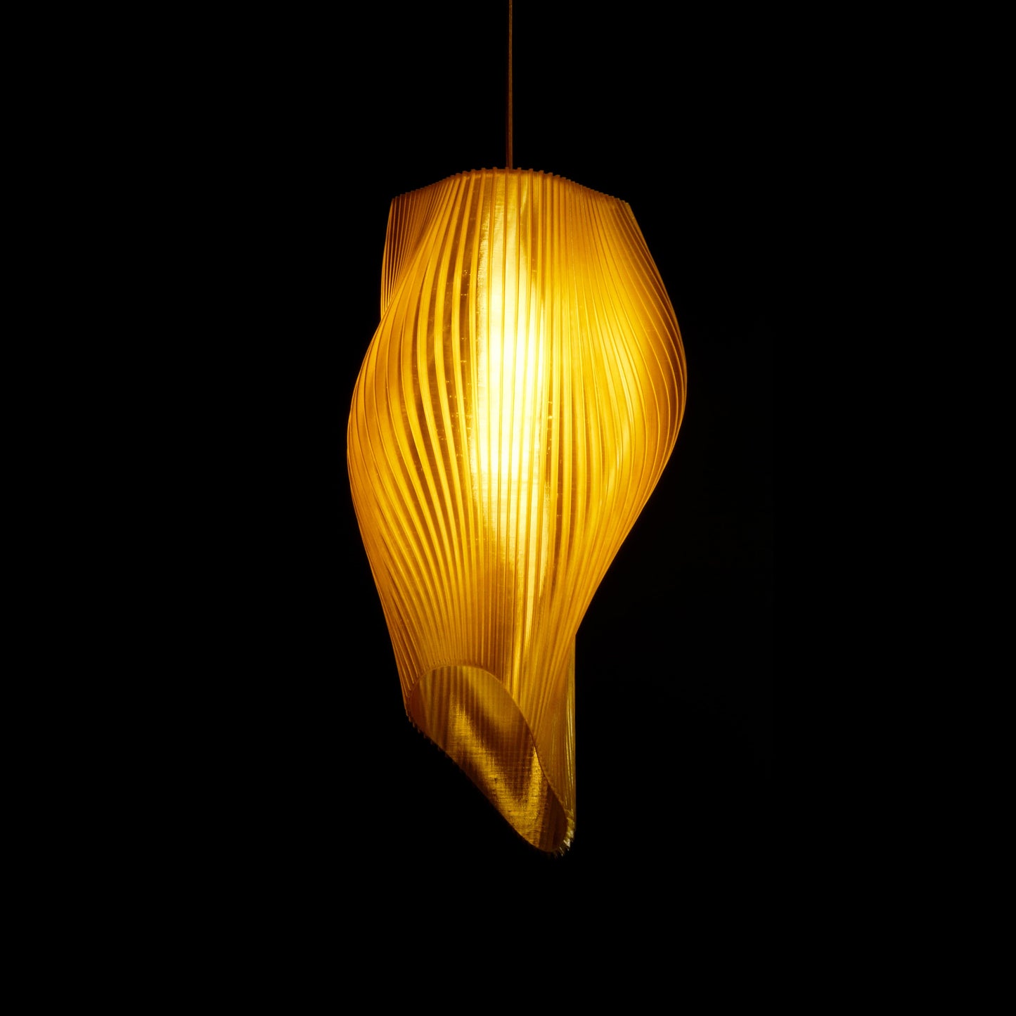 Sun Gold Long Wave Pendant Light illuminated, casting warm ambient glow across golden wave-inspired design