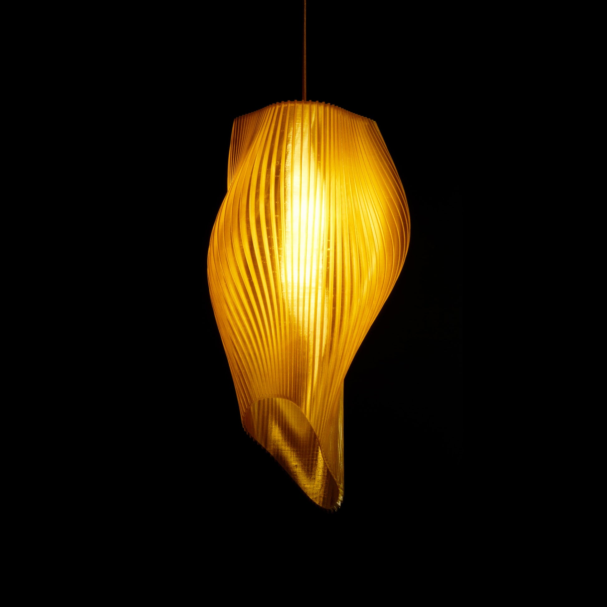 Sun Gold Long Wave Pendant Light illuminated, casting warm ambient glow across golden wave-inspired design