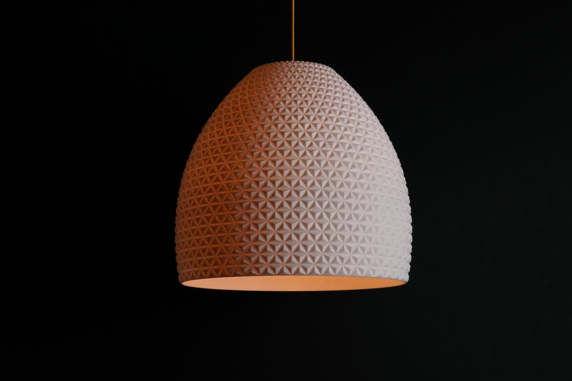 White geometric dome pendant light glowing with soft illumination, luxury sculptural ceiling fixture.