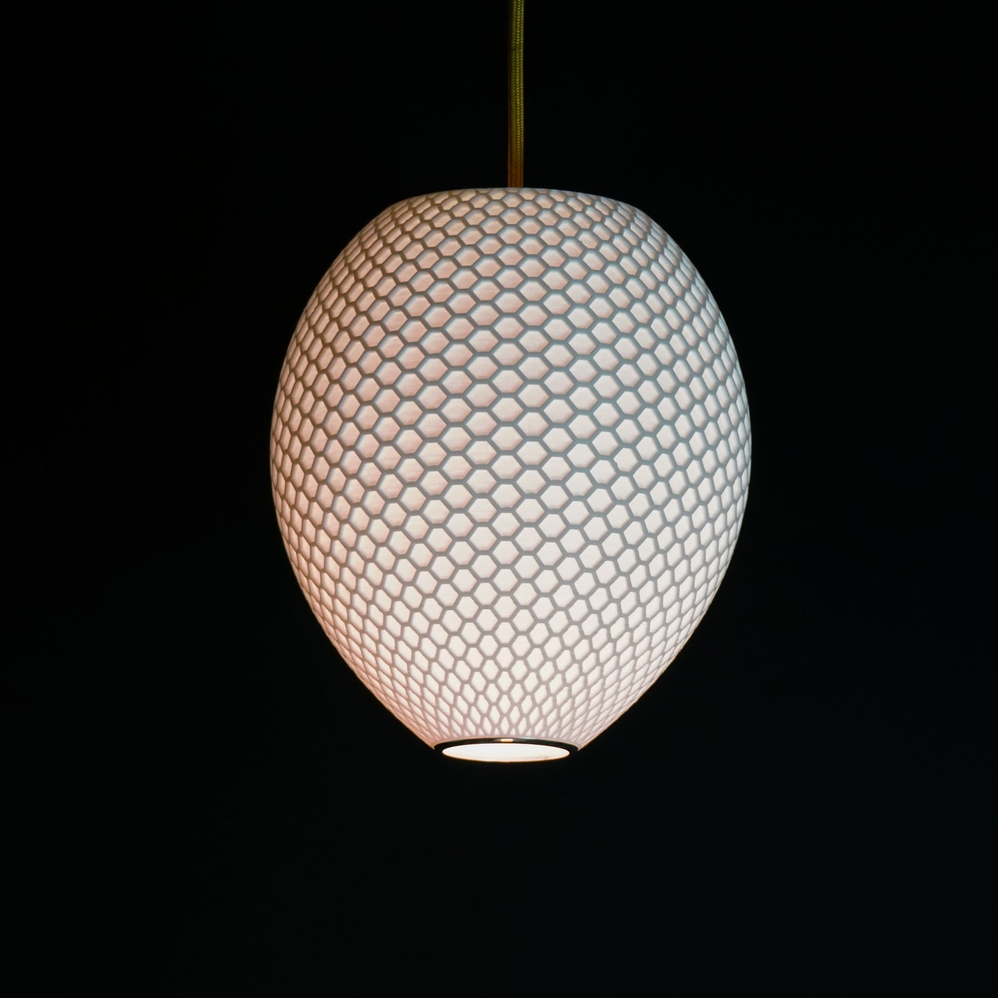 White Round Hive Pendant Light illuminated, casting ambient glow and highlighting geometric honeycomb pattern