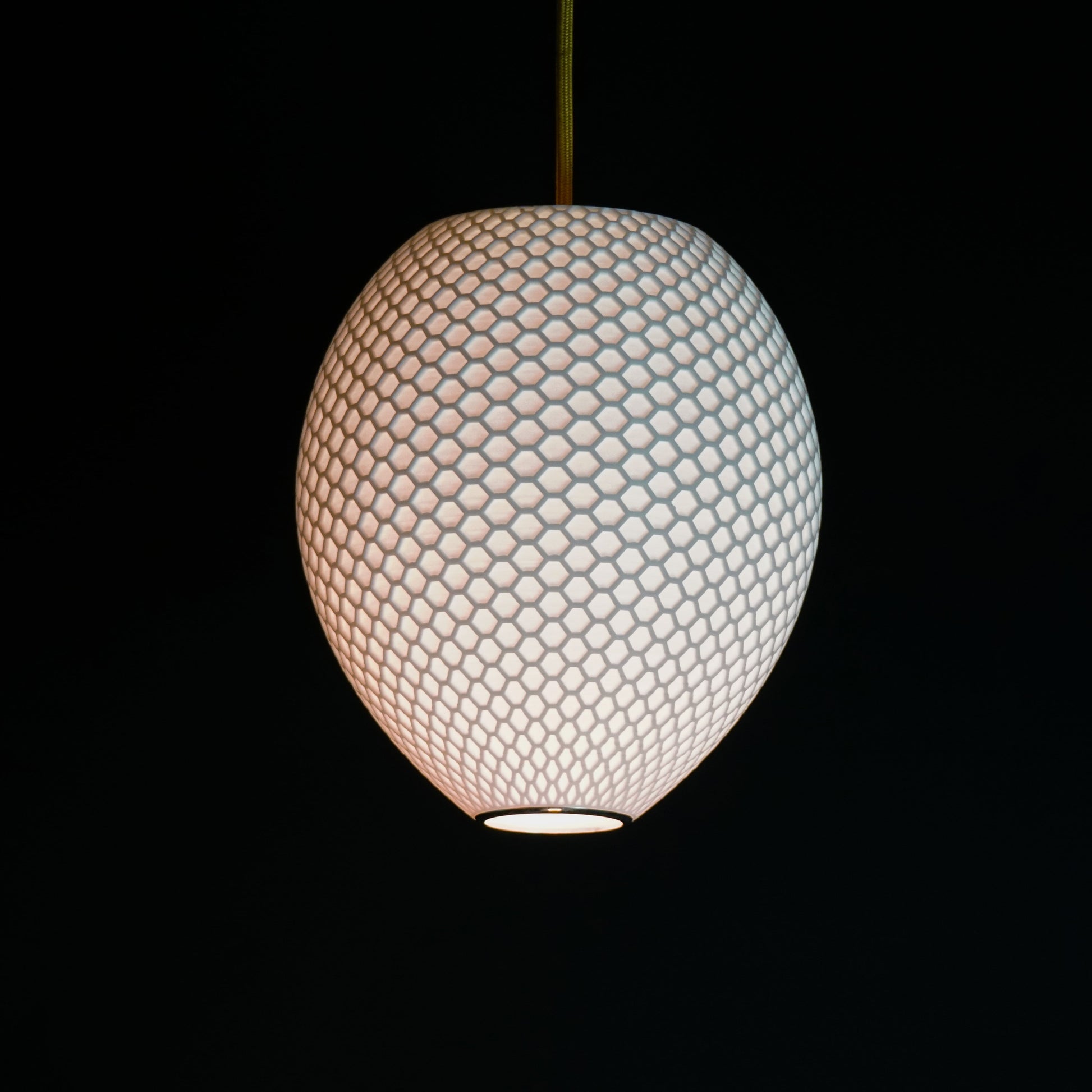White Round Hive Pendant Light illuminated, casting ambient glow and highlighting geometric honeycomb pattern